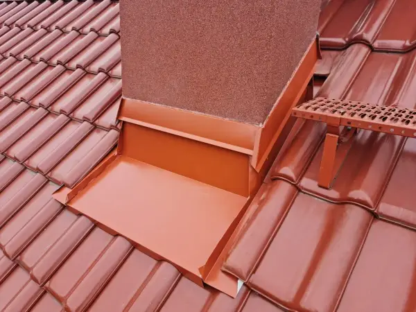 Opierzenie komina na felc dopasowane do koloru dachówki. Zwróć uwagę na precyzyjne łączenie blachy ze ścianą komina, co eliminuje ryzyko przecieków przy ulewnym deszczu. Długołęka